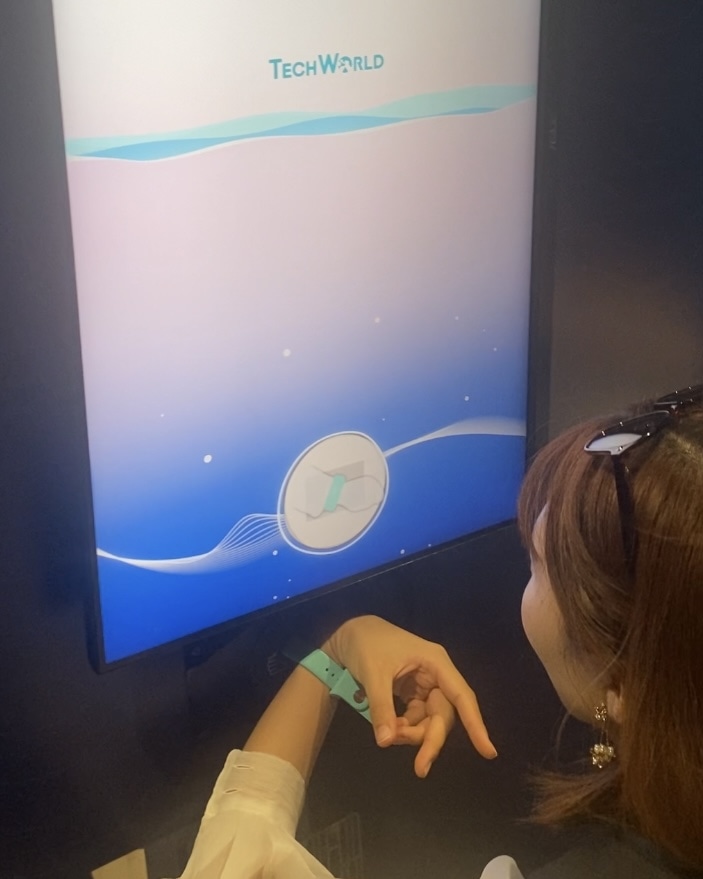 ProArtスクリーン（ASUS）、広視野角178°IPSパネルを搭載したHDRモニターに来場した際に着用したバンドをかざしている