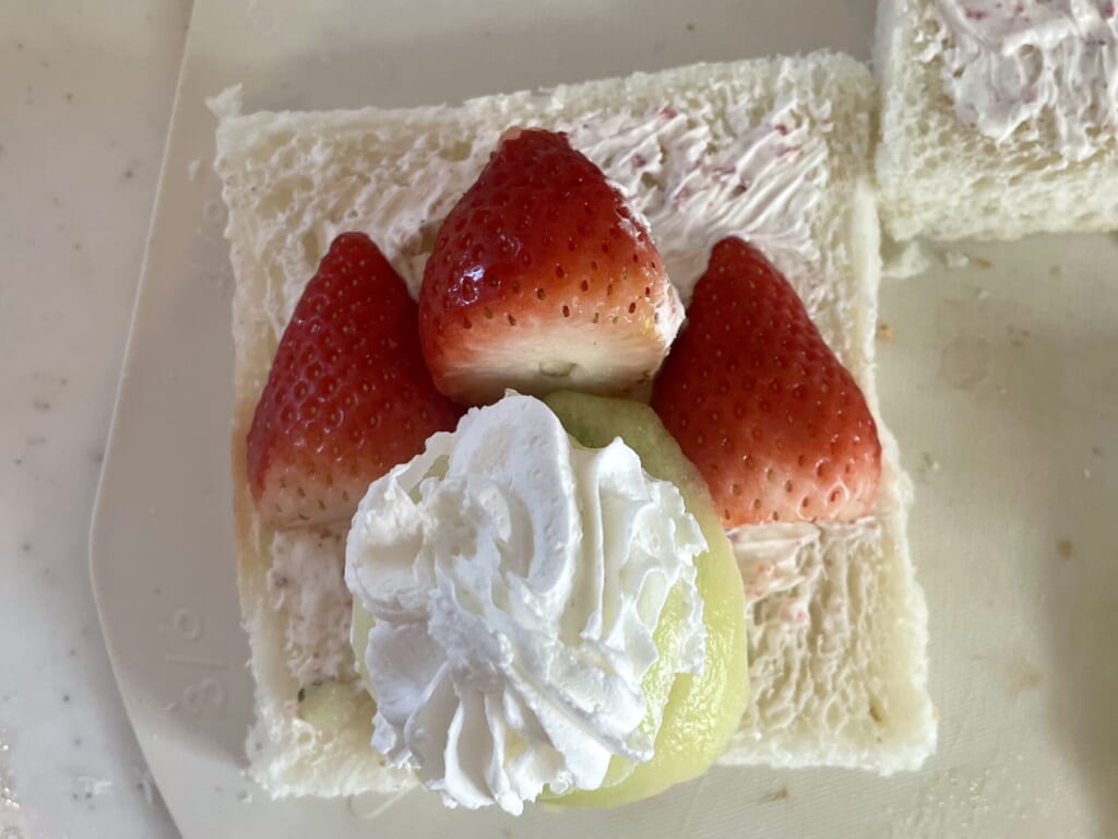 キウイを重ねてクリームをのせて、横に半分に切ったいちごをのせている