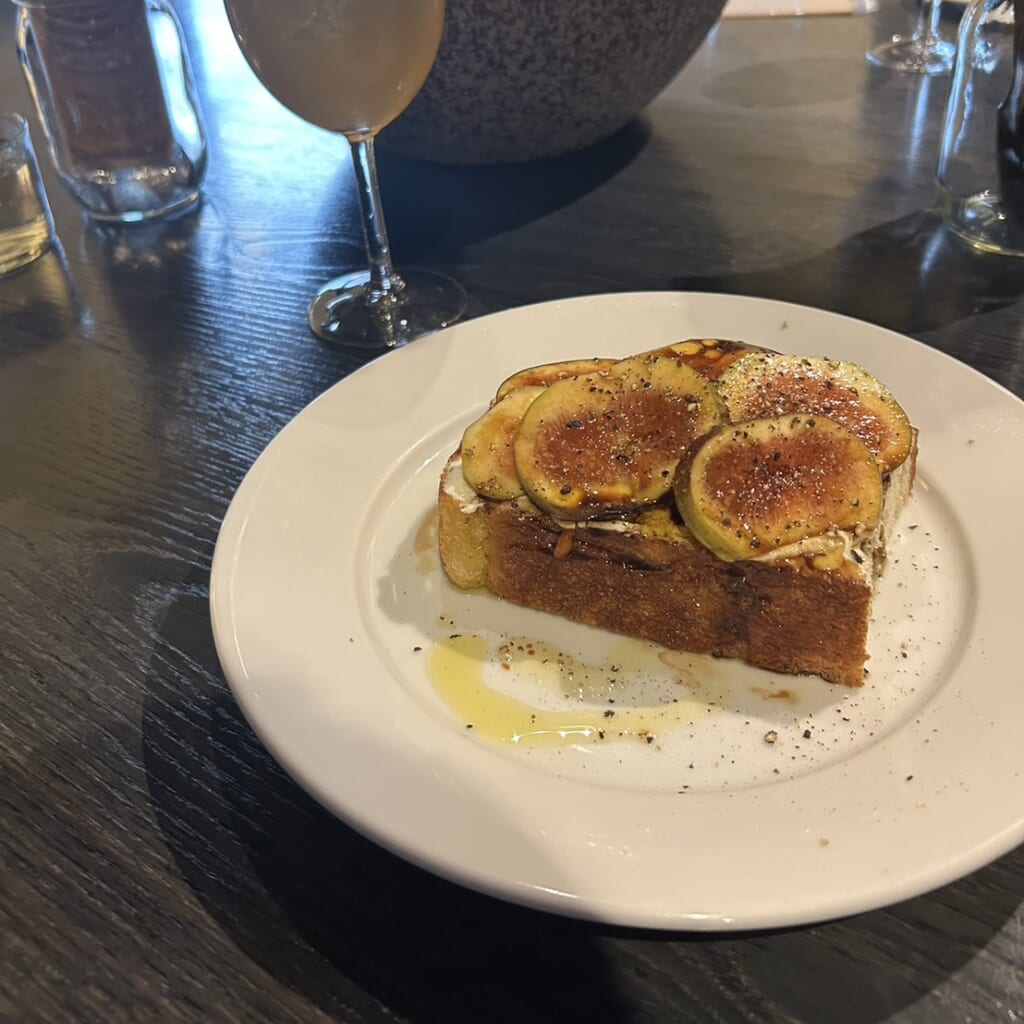 サンドを斜めから撮影した写真。分厚いフォカッチャの上にソース、無花果、ブラックペッパーがかかっている。