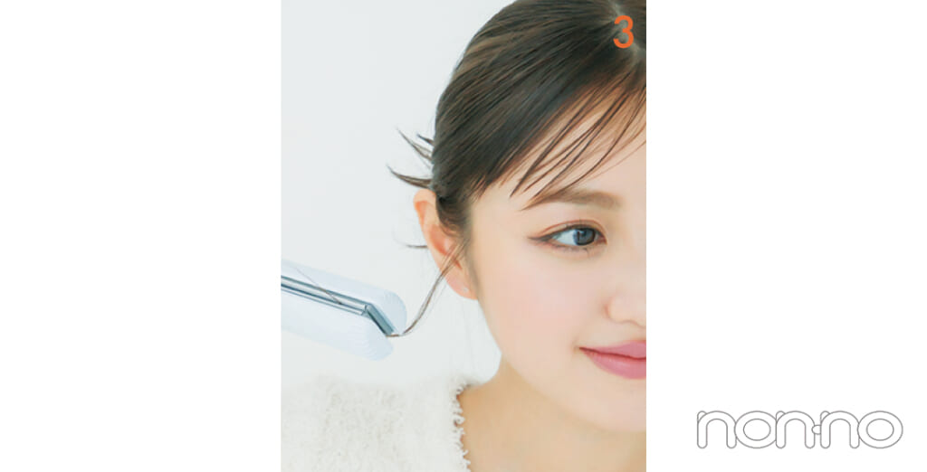 おくれ毛をストレートアイロンではさんでいる女性