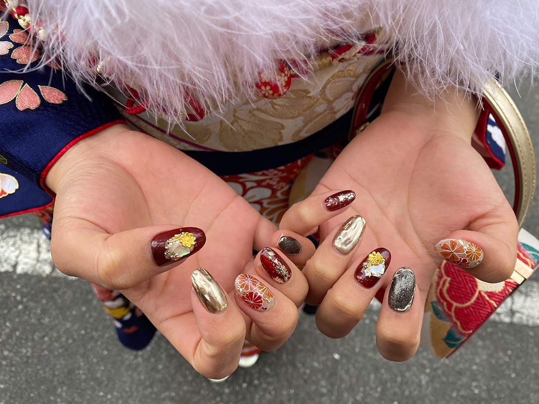 振袖を着た成人式ネイルの手元　赤ベースの花柄とゴールドで豪華にしたネイルデザイン