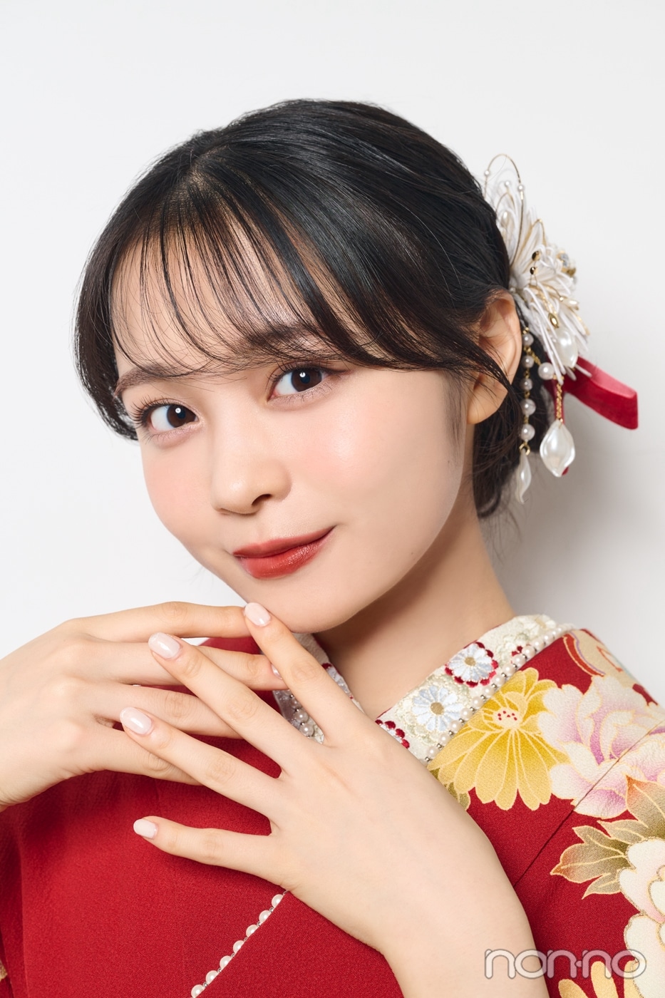 成人式ロングヘアアレンジ　シニョン姿に赤いリボンや白い花を飾った髪型の正面