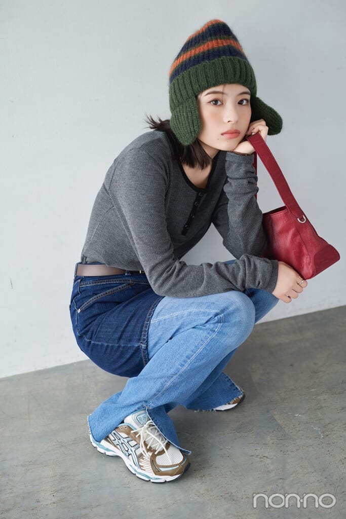 ヘンリーニットにデニムスカート、デニムパンツを重ねばきしてしゃがむ出口夏希