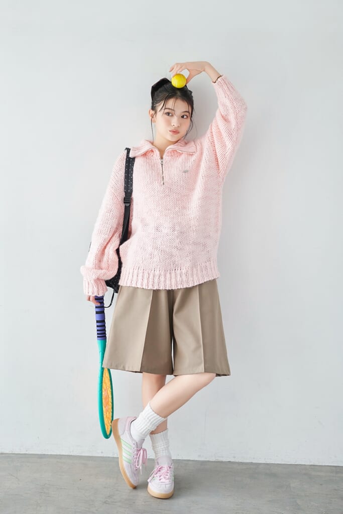ピンクのニットにベージュのハーフパンツ、ラケットを持った出口夏希の全身