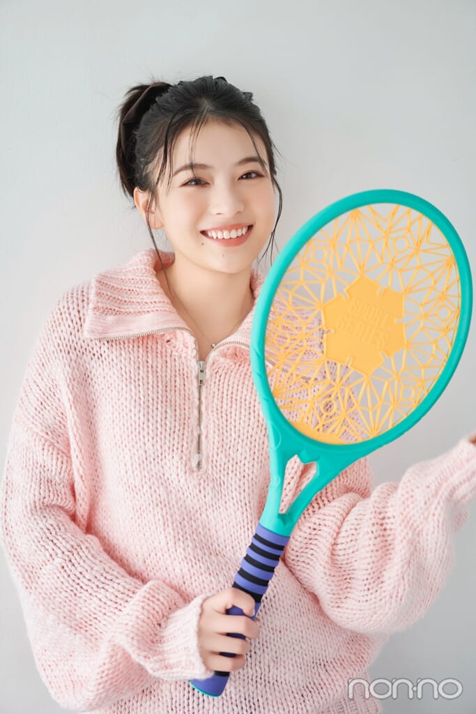ピンクのニットにラケットを持った出口夏希のバストアップ