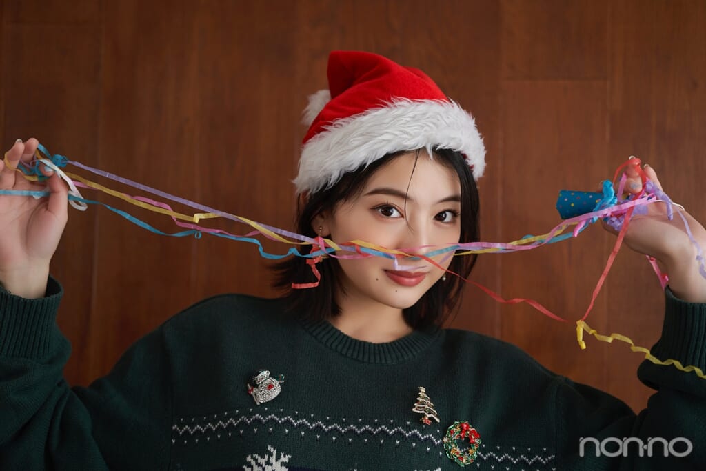 ブローチをつけた緑のトナカイニットを着た出口夏希のバストアップ