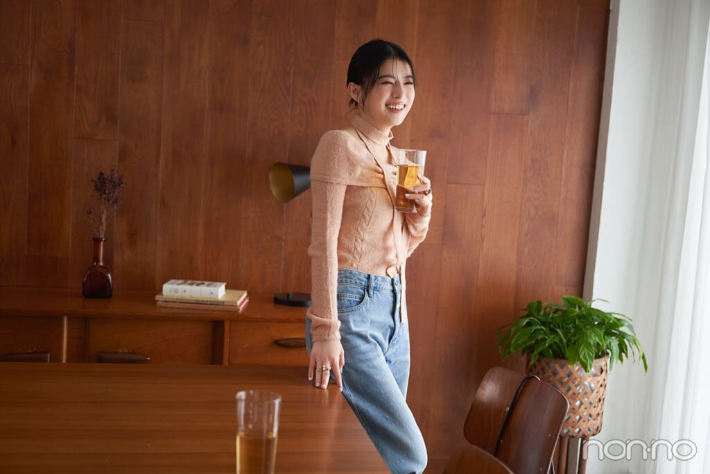 ピンクのオフショルニットにデニムパンツを履いた出口夏希