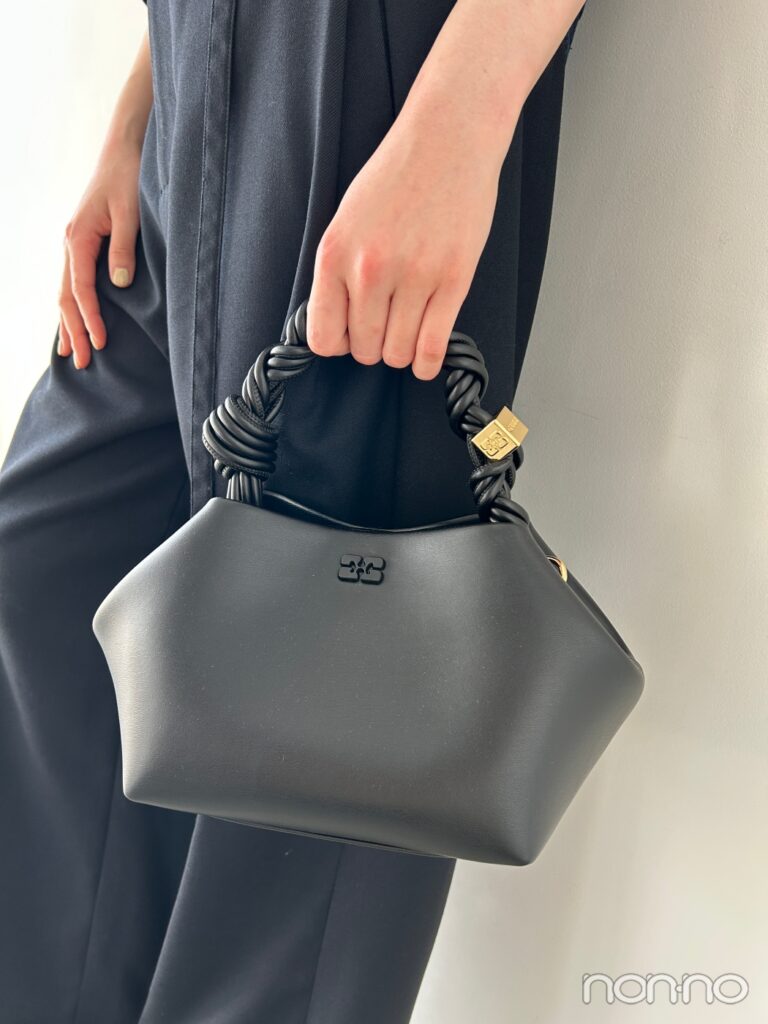 黒いレザーのミニバッグを持った手元の寄り