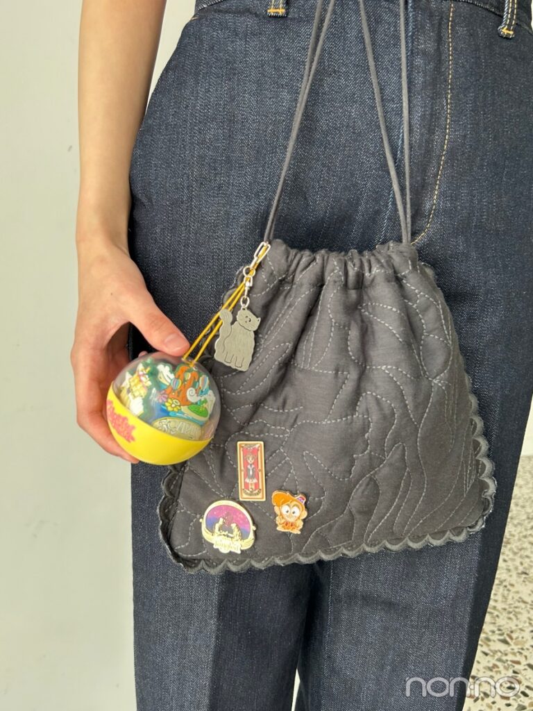 キーホルダーやピンバッジのついた黒の巾着バッグ