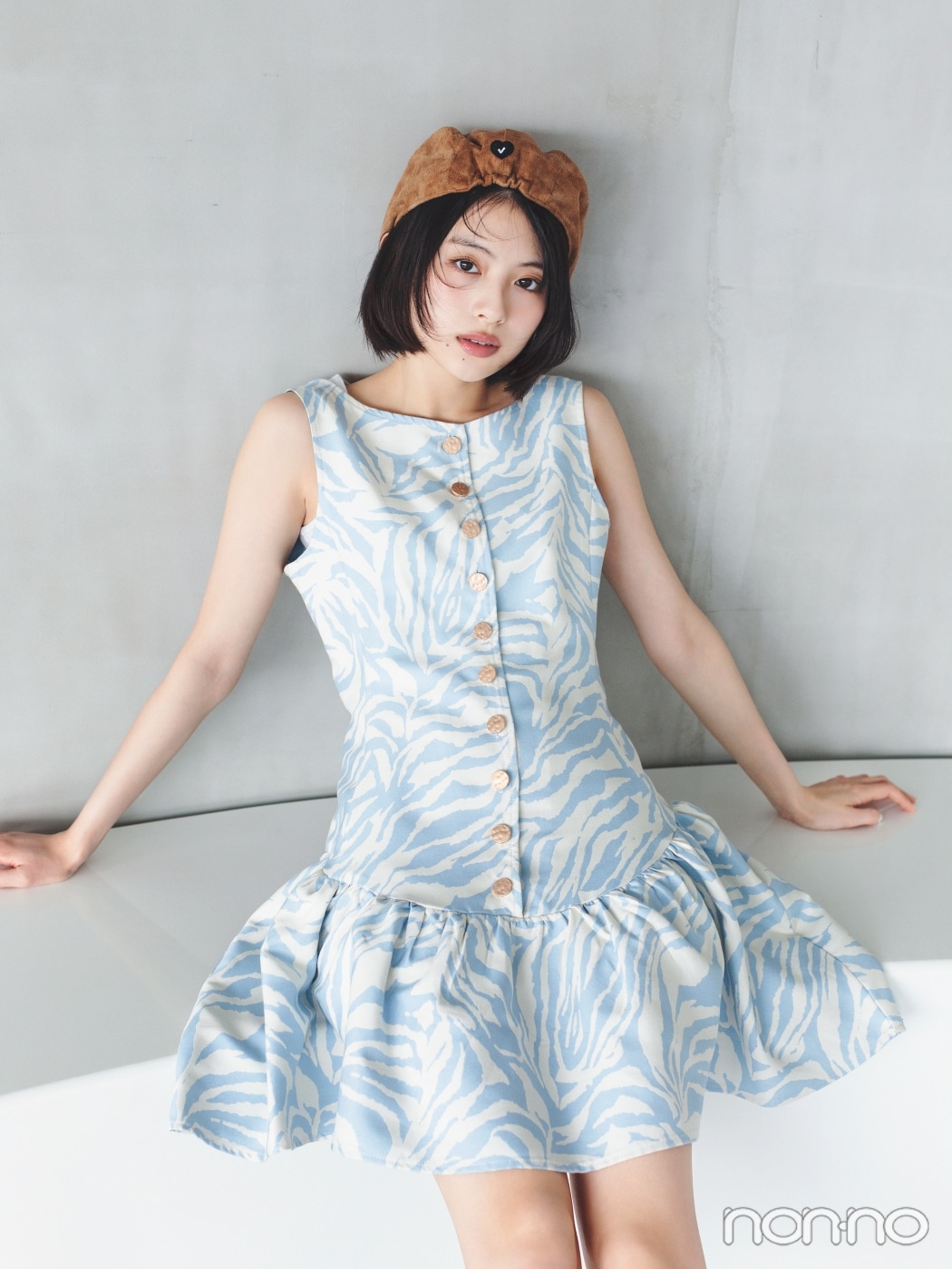 キャメルの帽子にゼブラ柄のワンピースを着て座る出口夏希の正面