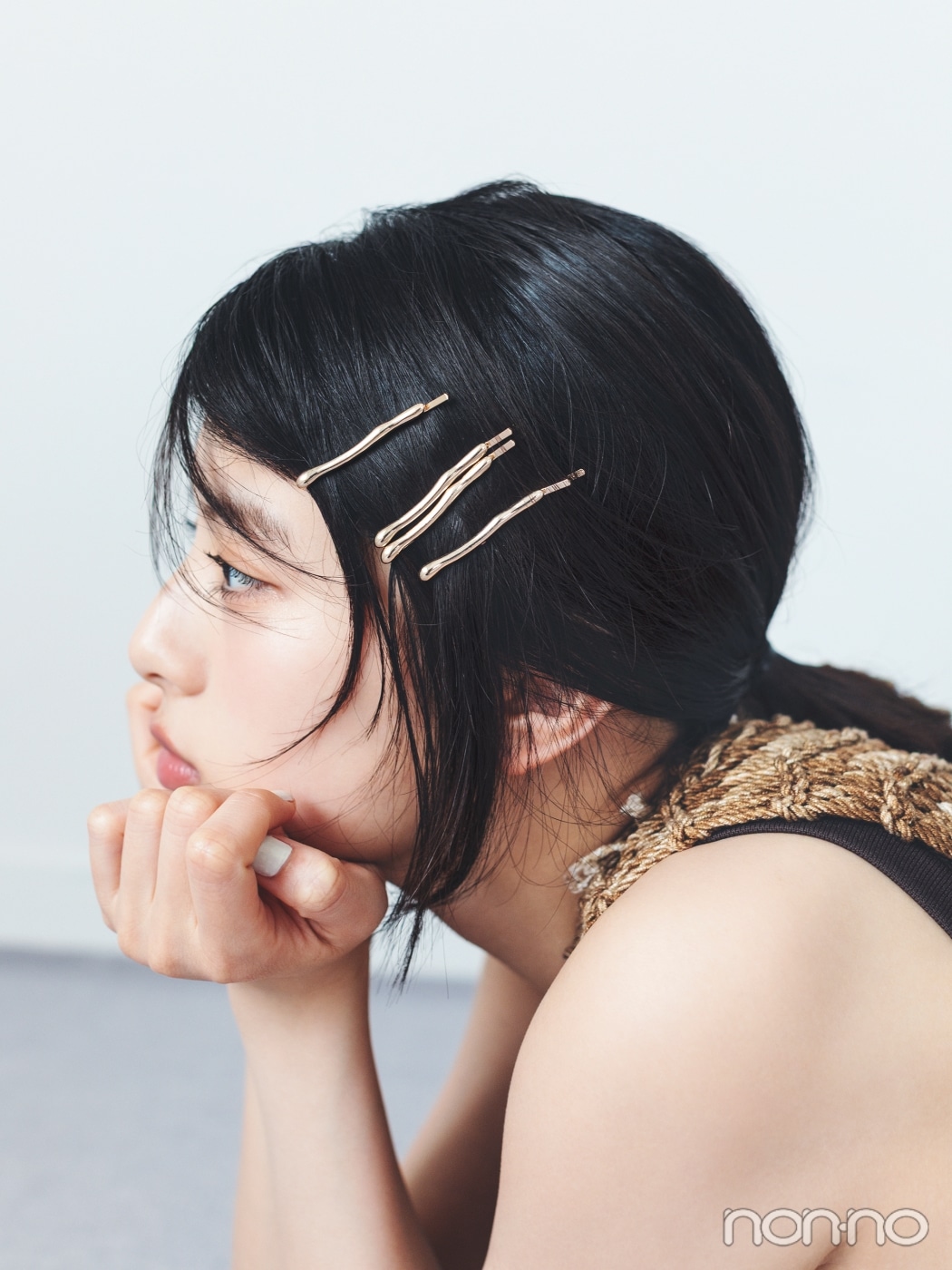 前髪にゴールドのピンを4本差して後ろで一つに結んだ、ほおづえをつく出口夏希