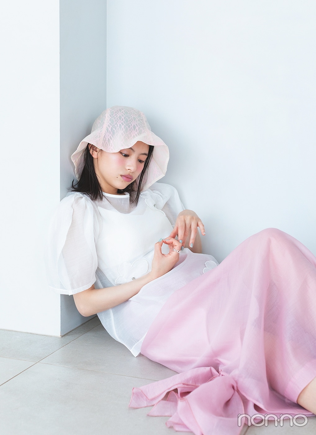 白いブラウスにピンクのスカートを履いて床に座る出口夏希