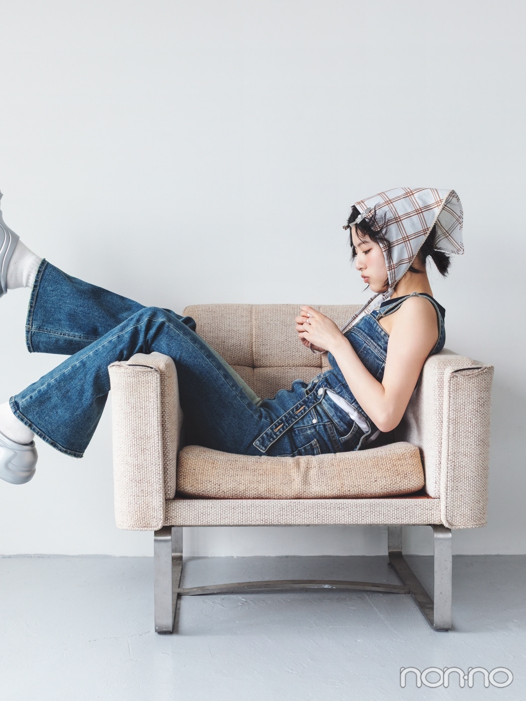 チェックのバブーシュカを巻いてソファーに横向きに座る出口夏希