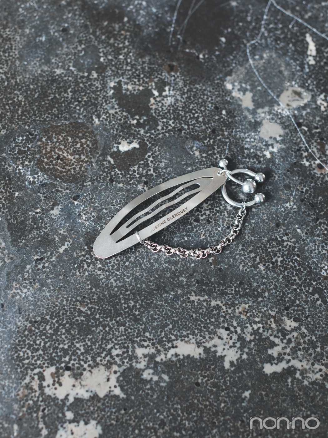 石の上に置かれたシルバーのチェーンつきピン