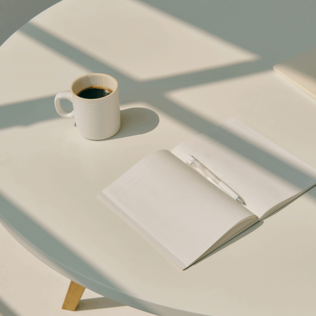 デスクにあるコーヒーとノートとペン