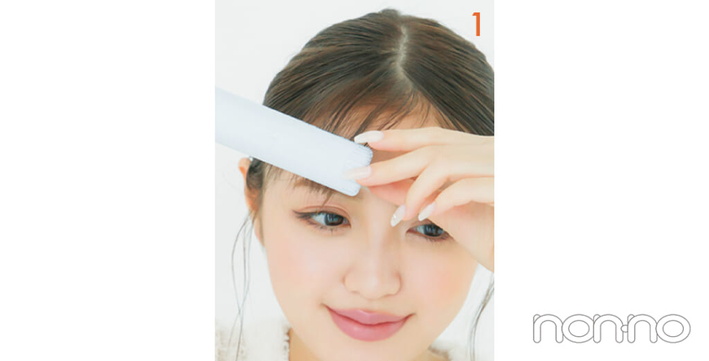 前髪をストレートアイロンではさんでいる女性