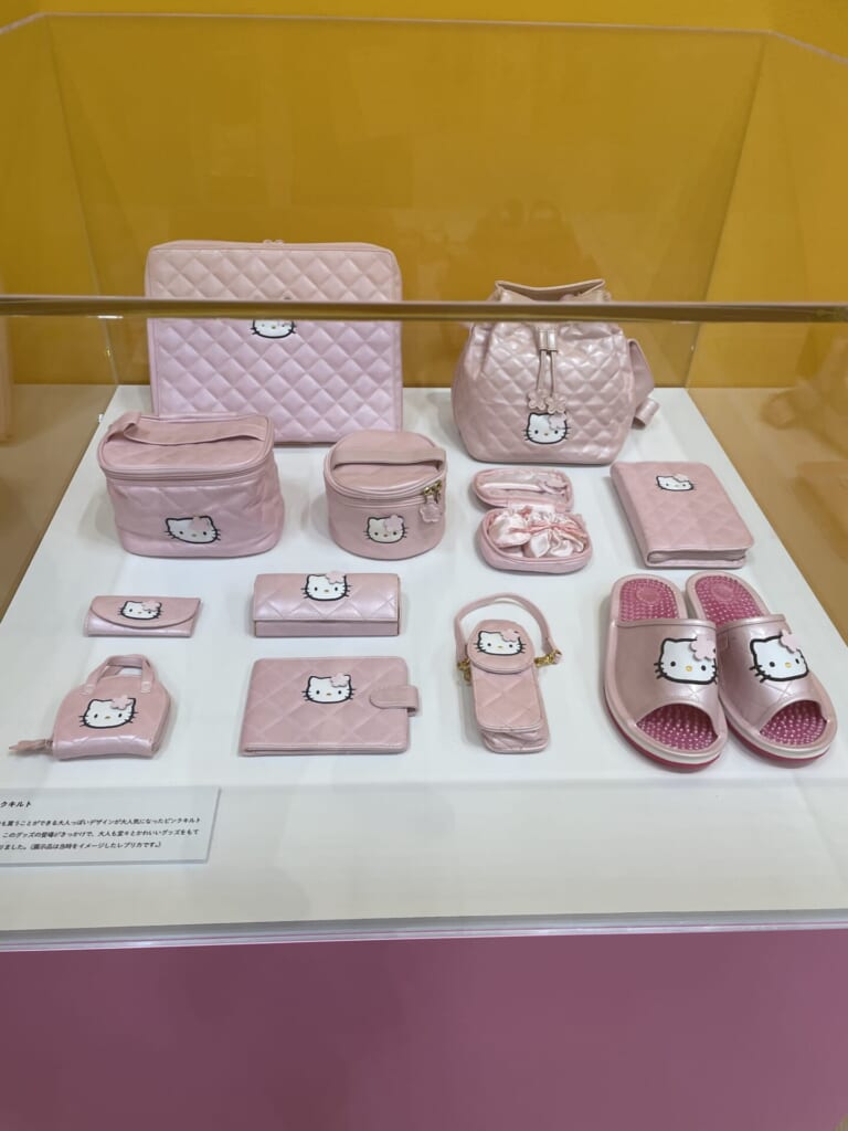 ピンク色でキルト記事のキティのグッズが並んでいる。バッグやポーチが多い。