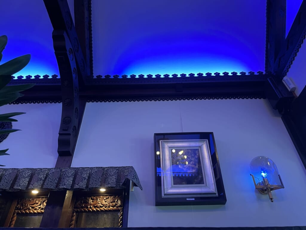 喫茶ソワレの内観。絵やランプが壁に飾られている。観葉植物が見切れている。青い灯りが特徴的。