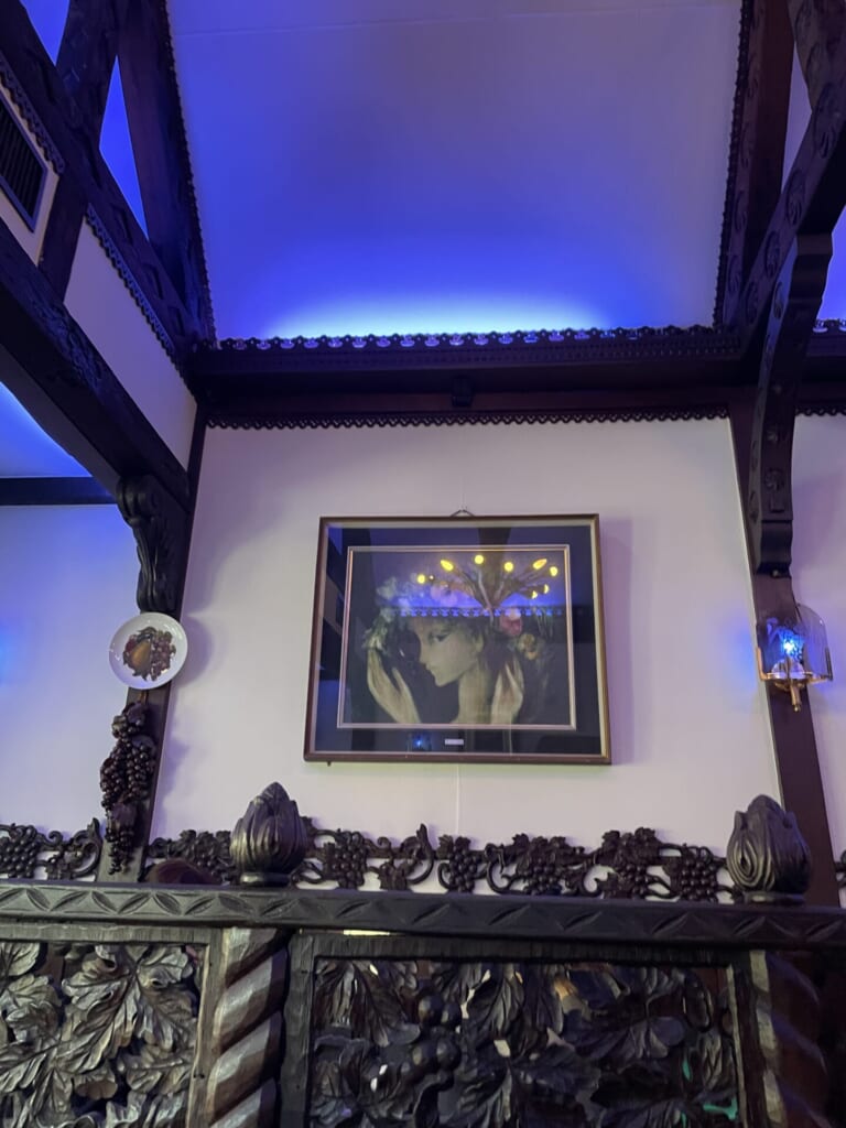 喫茶ソワレの内観。女性が描かれた絵や皿が壁に飾られている。青い灯りが特徴的。