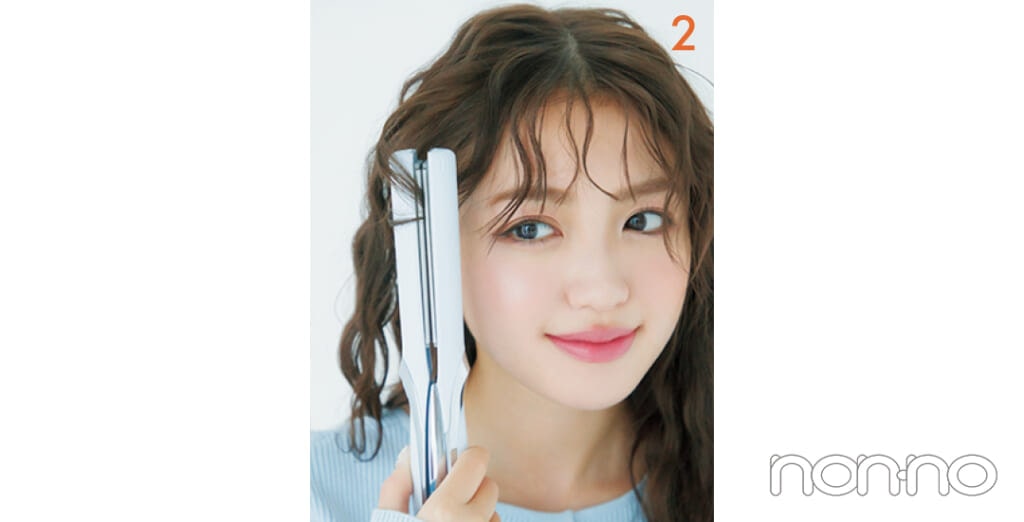 サイドの髪をストレートアイロンではさんでいる女性