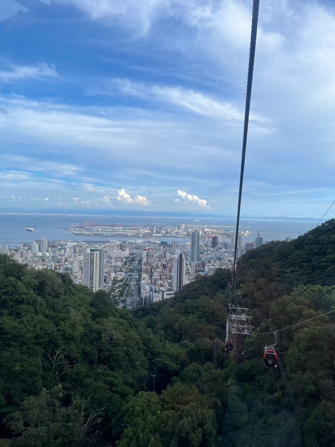 ロープウェイの中から見える景色。沢山の建物や海、空が見える。