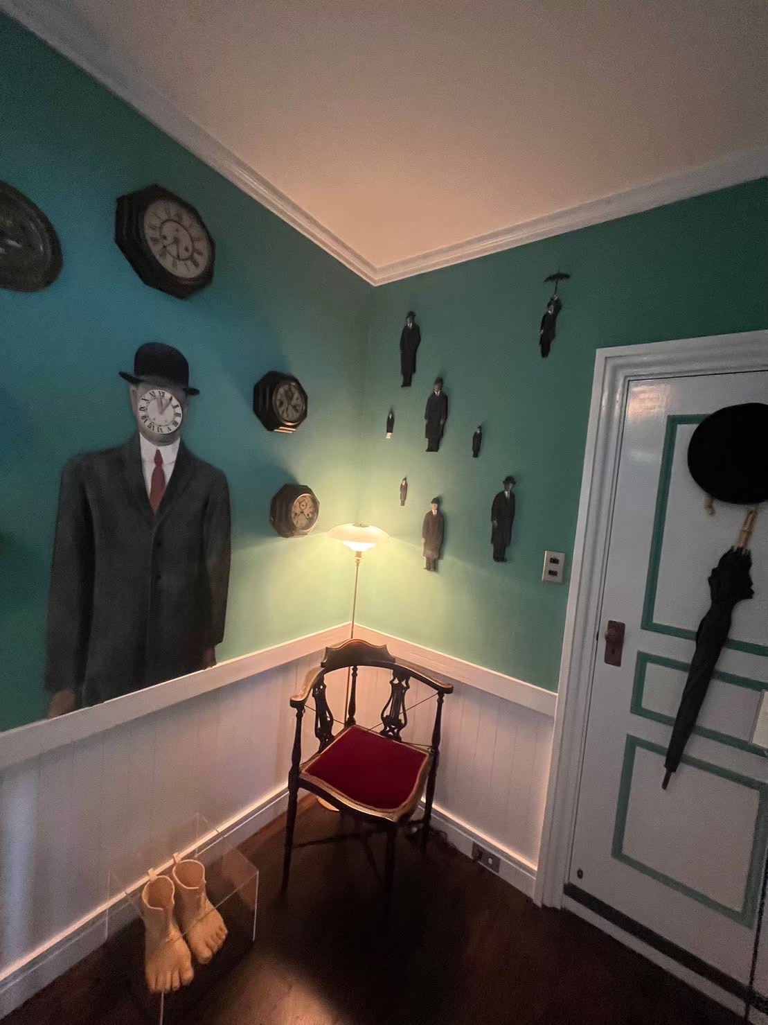 黄緑の壁に時計や人形がたくさん飾られている家の中の写真。