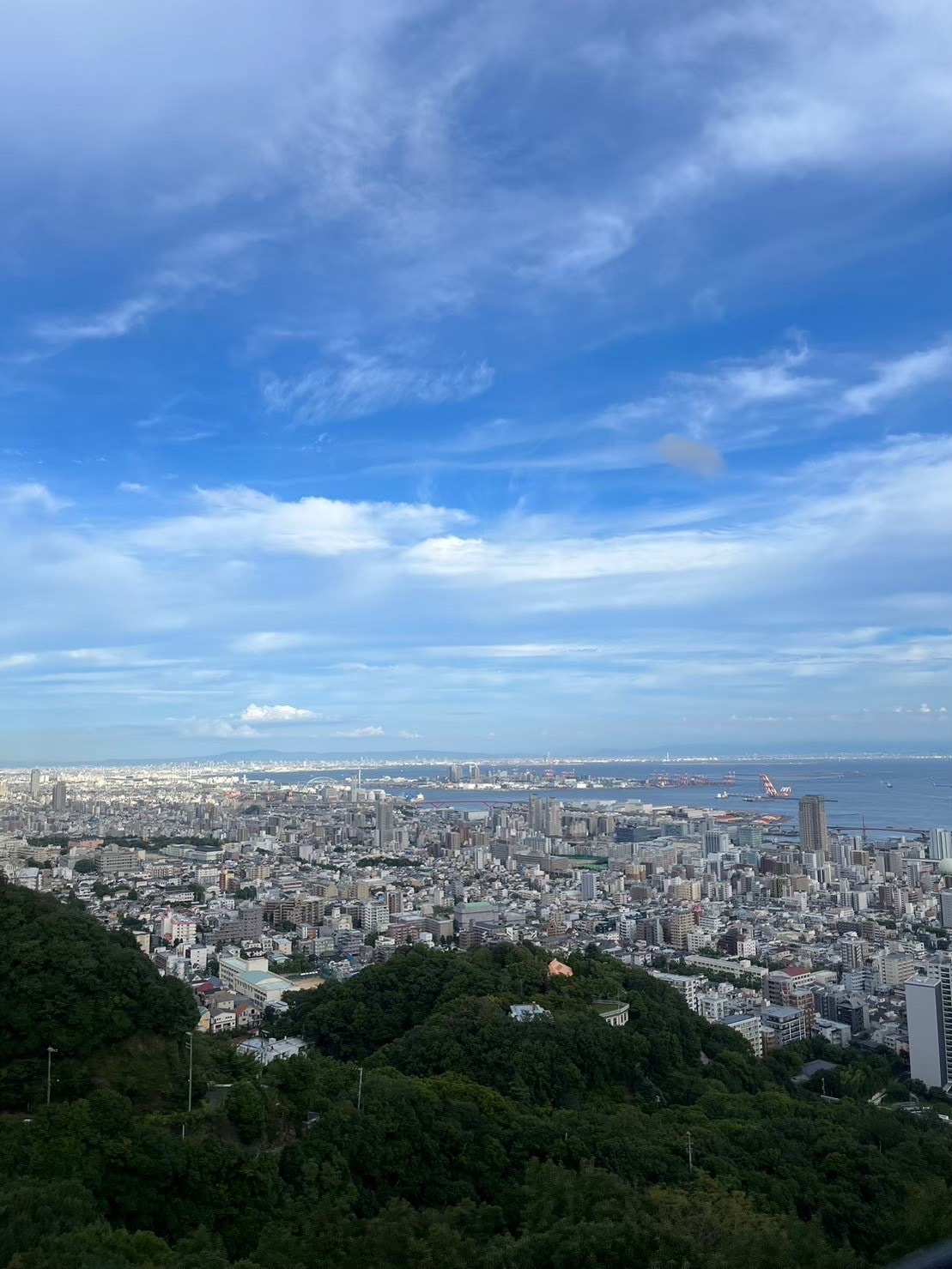 ロープウェイの中から見える景色。沢山の建物や海、空が見える。