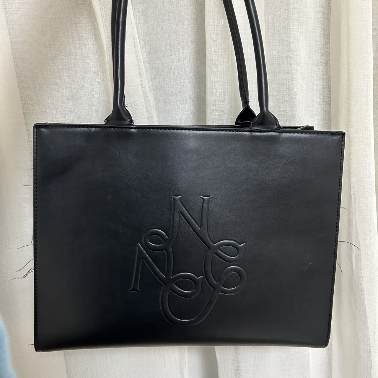 バッグの写真。大きな取っ手が付いている。ブランドロゴが真ん中に大きくデザインされている。